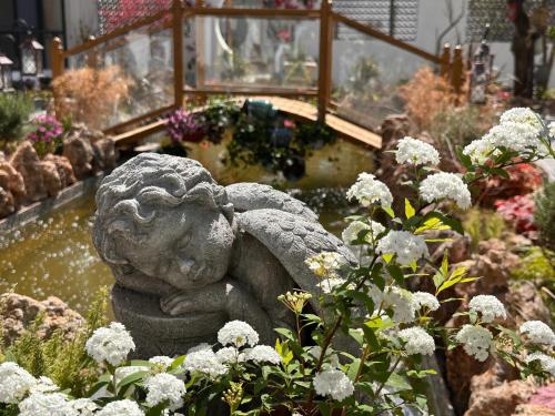 a stone angel statue in a garden with flowers at Lijiang Hengchang Baoyin Mohuakai Inn in Lijiang