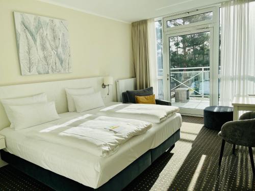 ein Schlafzimmer mit großem Bett und großem Fenster in der Unterkunft Strandhotel Fischland in Dierhagen