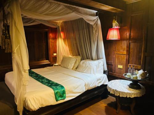 a bedroom with a canopy bed and a table at Seven Senses Guesthouse in Chiang Mai