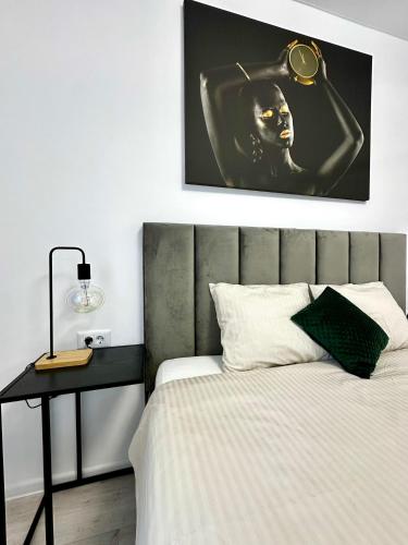 a bedroom with a bed with a table and a picture at Elite Studio Militari Residence in Chiajna