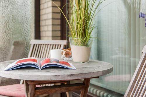 a table with a book and a plant on it at Büngers Apartment-Hotel mit Sommerstrandkorb & Gartensauna in Strande