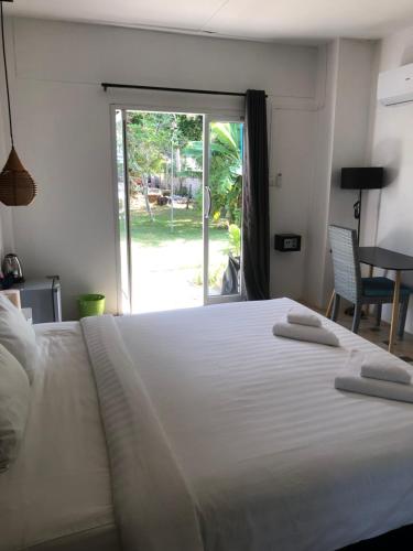 a bedroom with a large white bed with a sliding glass door at Wild Wood x Hansa Beach Fitness Resort in Thongsala