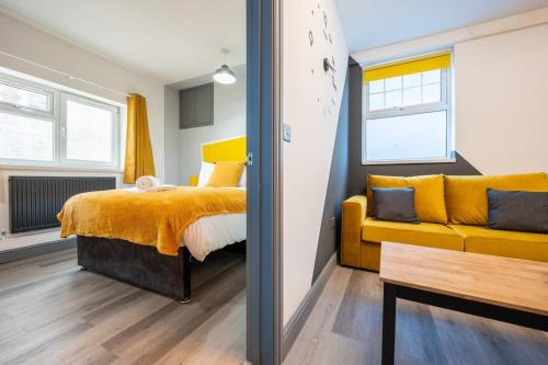 a bedroom with a bed and a yellow couch at Free Parking - The Coach House A by Tŷ SA in Cardiff