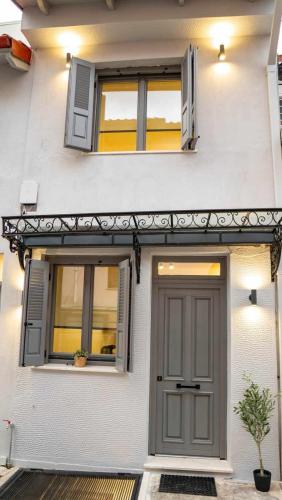 una casa bianca con una porta grigia e due finestre di 1900 Apartments Ioannina a Ioannina