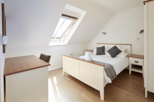 a white bedroom with a bed and a window at Monmouth Retreat Cottage in Beckington