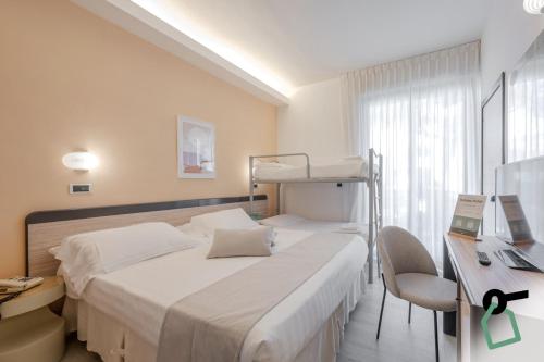 a bedroom with a bed and a desk with a laptop at HOTIDAY Room Collection - Giulianova in Giulianova