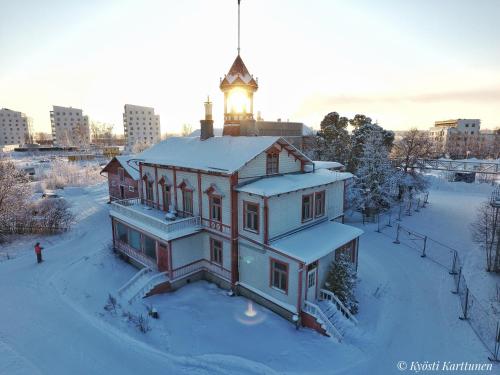 a house with a tower on top of it in the snow at Hostel Cafe Huvila in Oulu