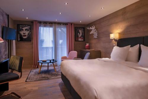 a hotel room with a large bed and a table at Chalet-Hôtel La Marmotte, La Tapiaz & SPA, The Originals Relais in Les Gets