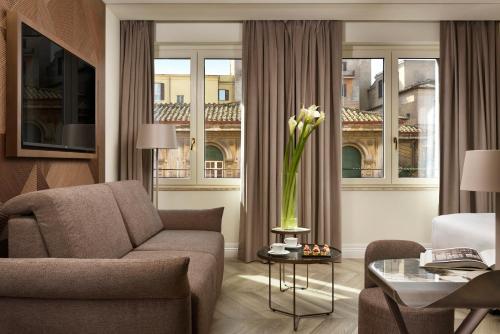 un soggiorno con divano e tavolo con vaso di fiori di FH55 Grand Hotel Palatino a Roma
