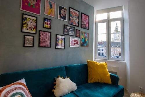 um sofá azul num quarto com fotografias na parede em Hesdin Appart Holidays 3 em Hesdin