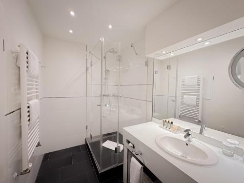 ein weißes Badezimmer mit Waschbecken und Dusche in der Unterkunft Strandhotel Fischland in Dierhagen