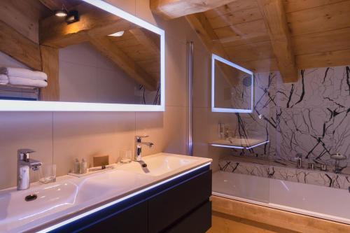 a bathroom with a sink and a bath tub at Chalet-Hôtel La Marmotte, La Tapiaz & SPA, The Originals Relais in Les Gets