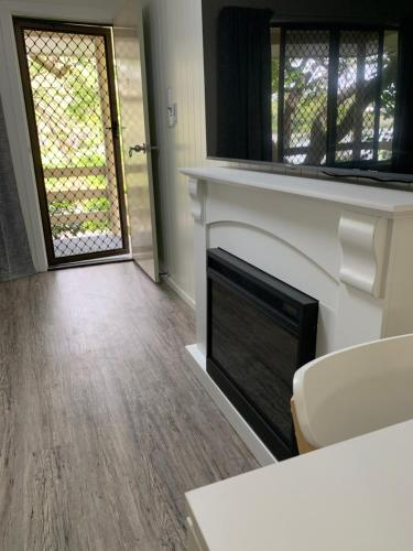 a living room with a fireplace and a door at Turtle Cove Lake Front Cabin 300m To Beach in Hervey Bay