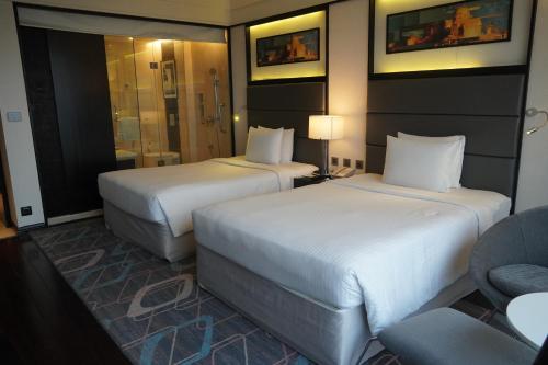 a hotel room with two beds and a chair at Crowne Plaza Pune City Centre by IHG in Pune