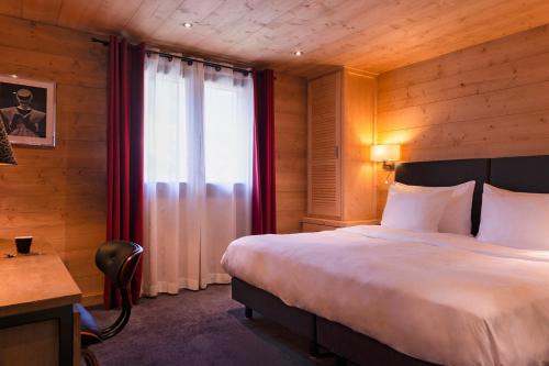 a bedroom with a large bed and a window at Chalet-Hôtel La Marmotte, La Tapiaz & SPA, The Originals Relais in Les Gets