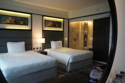 a hotel room with two beds and a mirror at Crowne Plaza Pune City Centre by IHG in Pune