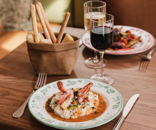 a table with two plates of food and a glass of wine at Crowne Plaza Lyon - Cité Internationale in Lyon