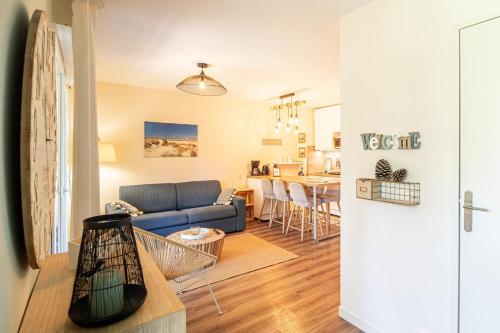 un salon avec un canapé bleu et une cuisine dans l'établissement Comfortable apartment with pool, à Moliets-et-Maa