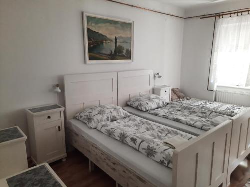 a bedroom with two beds and a picture on the wall at Nosztalgia Vendégház in Bogács