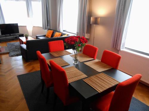 a dining room with a table and red chairs at VILLA EXPO in Brussels