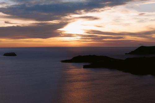 a sunset over the ocean with rocks in the water at Nelya Suites in Megalokhori