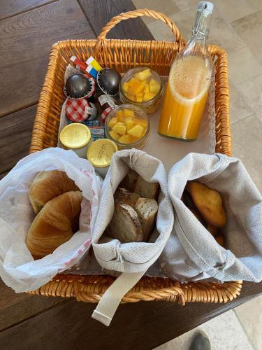 a basket of bread and other foods and a bottle of orange juice at Gîte La Cabuche proche du zoo de Beauval in Thenay