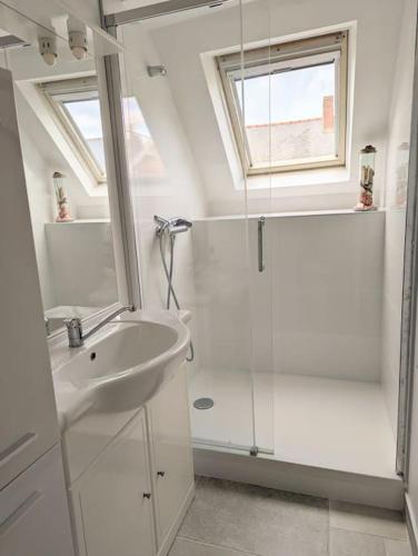 une salle de bain blanche avec une douche et un lavabo dans l'établissement Appartement face à la plage du val André, à Pléneuf-Val-André