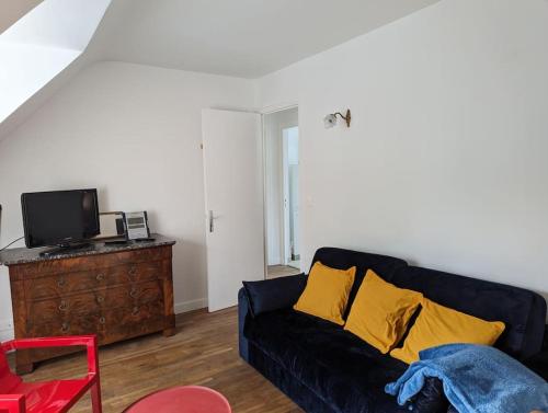ein Wohnzimmer mit einem schwarzen Sofa und gelben Kissen in der Unterkunft Appartement face à la plage du val André in Pléneuf-Val-André