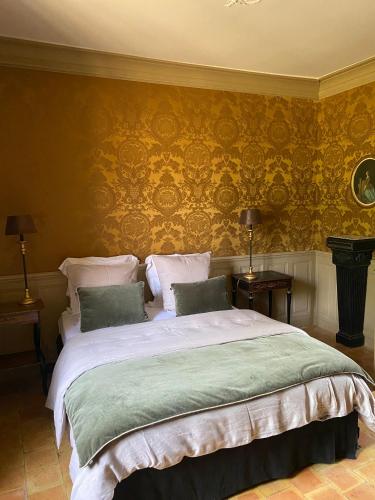 Dancé的住宿－Le Manoir du Plessis，一间卧室配有一张带黄色壁纸的大床