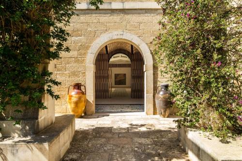 an archway with two large vases in a building at Secolario Masseria del Viverbene in Palmariggi