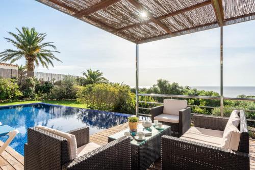 an outdoor patio with a table and chairs next to a swimming pool at Villa La Martina in Sant Lluis