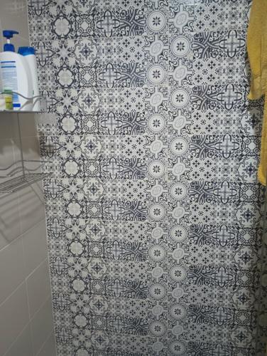 a bathroom with a shower curtain with a patterned wall at Ssana in Aïn Harrouda