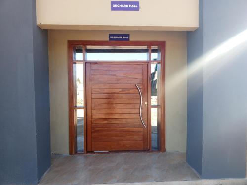 una puerta de madera en un edificio con un cartel en Orchard Mist Lodges and Events en Kabwe