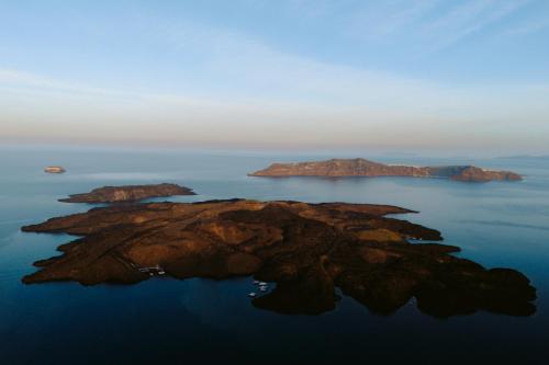 une île dans l'eau au coucher du soleil dans l'établissement Nelya Suites, à Megalochori
