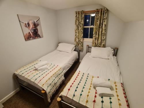ein Schlafzimmer mit 2 Betten und ein Bild einer Kuh in der Unterkunft The Riverside in Lechlade