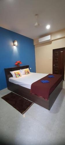 a bedroom with a large bed with a blue wall at OYO Flagship Relax Stay in Verem