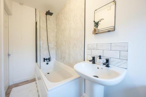 een witte badkamer met een wastafel en een bad bij Silver Street by Tŷ SA in Troed-y-rhiw