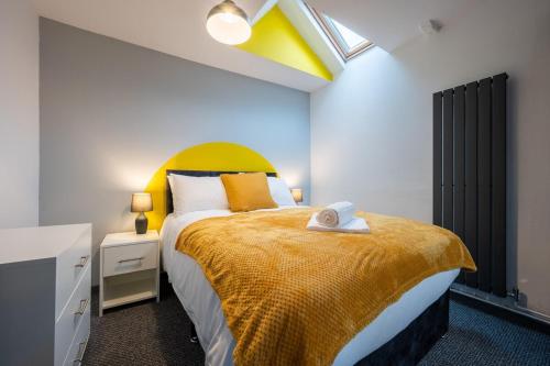 a bedroom with a bed with a yellow headboard at Free Parking - The Coach House B by Tŷ SA in Cardiff