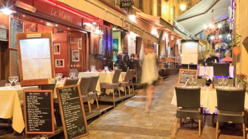 une femme en robe blanche traversant un restaurant dans l'établissement Kiss, à Cannes
