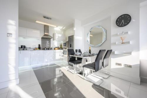 a white kitchen with a dining table and a mirror at Skyline, by Tŷ SA - Stay Central with Free Parking in Cardiff