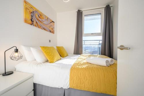 a bedroom with a bed with yellow pillows and a window at Skyline, by Tŷ SA - Stay Central with Free Parking in Cardiff