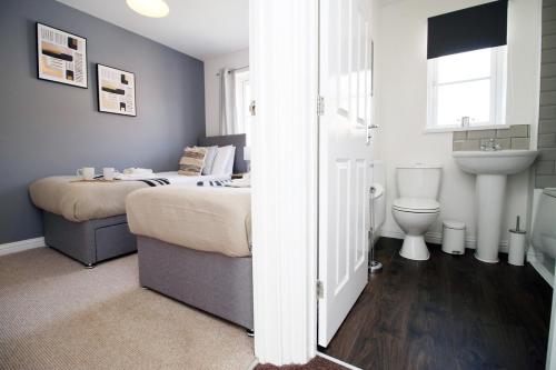 1 dormitorio con 2 camas, lavabo y aseo en Gwent View by Tŷ SA en Newport