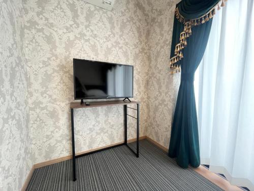 a flat screen tv sitting on a stand next to a window at Tokyo Holiday Hotel in Tokyo