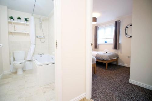 a bathroom with a toilet and a sink and a bed at Sleeps 6 - Argosy Way by Tŷ SA in Newport
