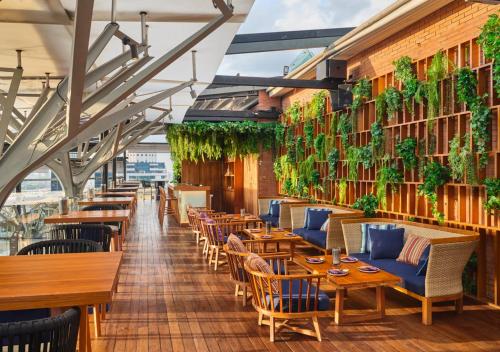 a restaurant with tables and chairs and plants at Fraser Suites Sukhumvit Bangkok in Bangkok
