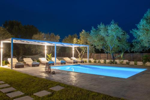 a swimming pool in a backyard at night at Armonia Boutique Hotel in Meson Yerakarion