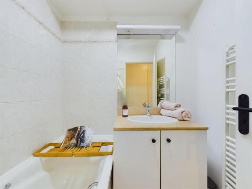 een witte badkamer met een wastafel en een bad bij Cozy Studio vue Parc in Rueil-Malmaison