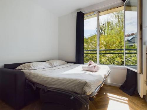 een slaapkamer met een bed en een groot raam bij Cozy Studio vue Parc in Rueil-Malmaison