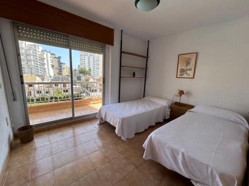 a bedroom with two beds and a large window at Apartamento duplex LOS IRIS solo familias in Playa de Gandia