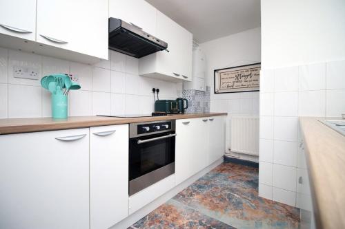 cocina con armarios blancos y fogones en Junctions Way by Tŷ SA -3 bed in Newport en Newport